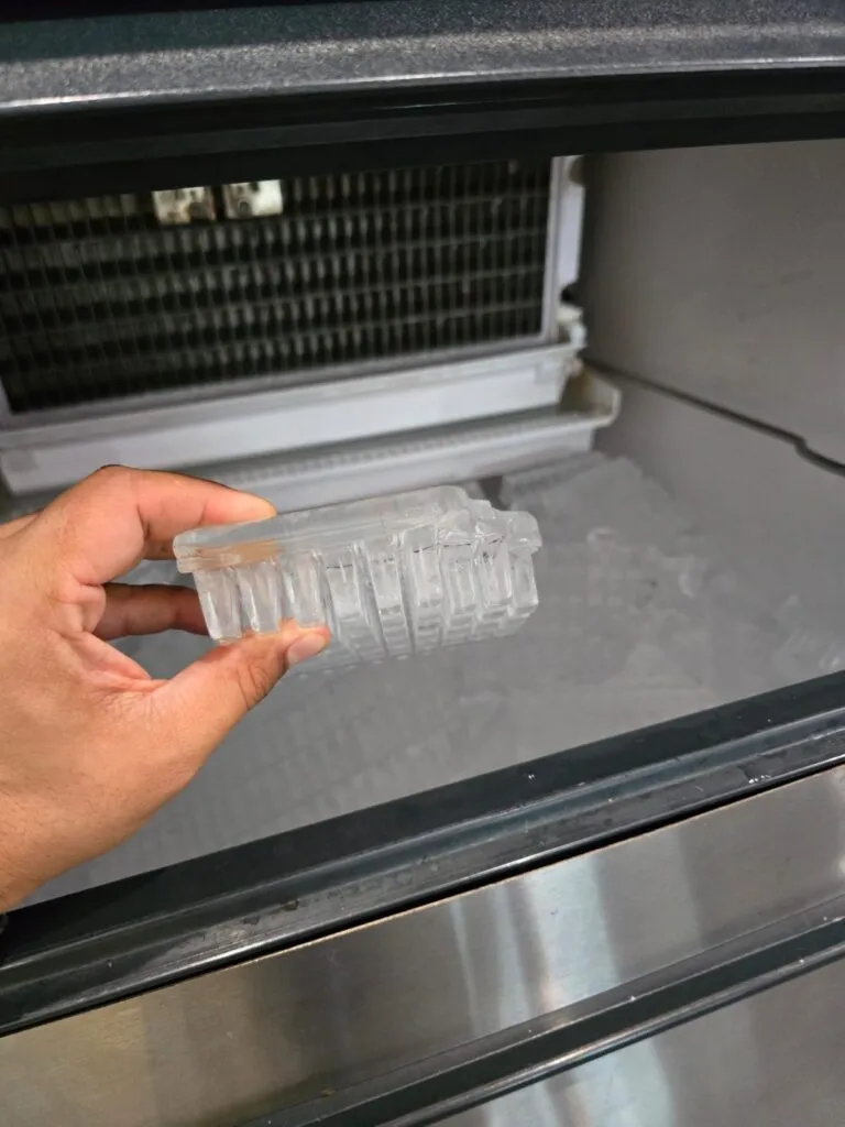 A technician holding poorly formed ice block from an ice machine