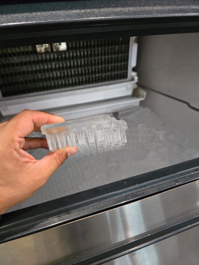 A technician holding poorly formed ice block from an ice machine